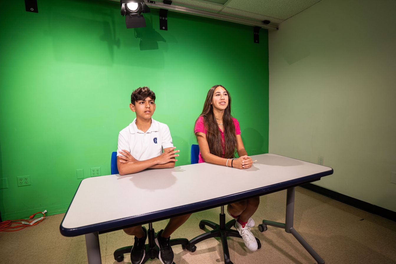 Two middle school students standing in as RSN anchors