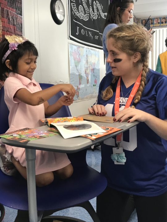 A young Gulliver student smiles as she does arts and crafts with a high school mentor