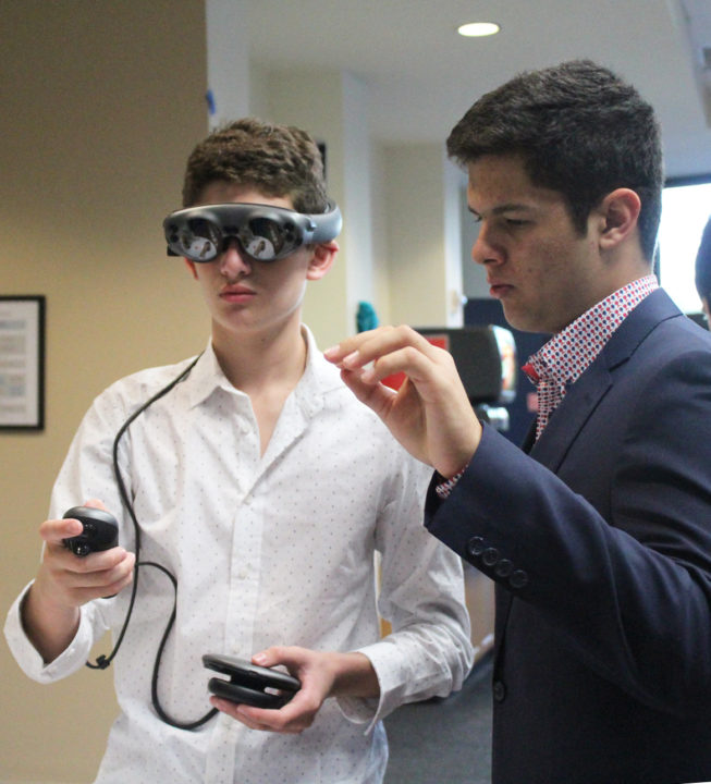 Two male students test a virtual reality console in a tech workshop