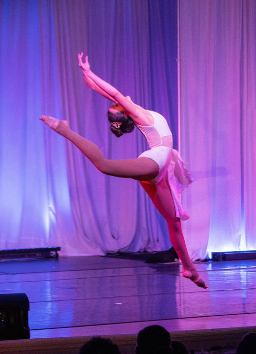 Young dancer performs and arabesque on stage