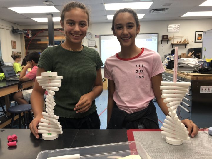 Two female students smiling with engineering projects.