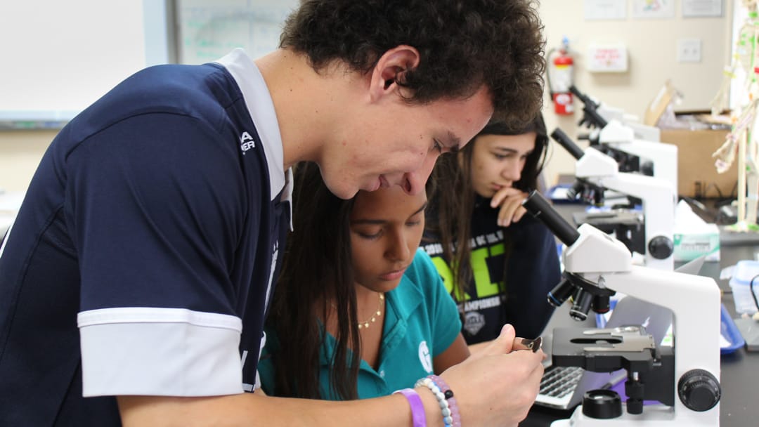 Two upper school students looking at a microscope in Biomedical science class