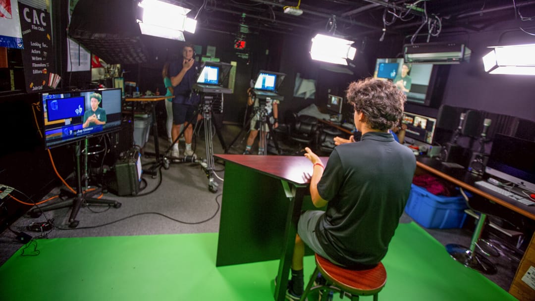 Student broadcasting against a green screen