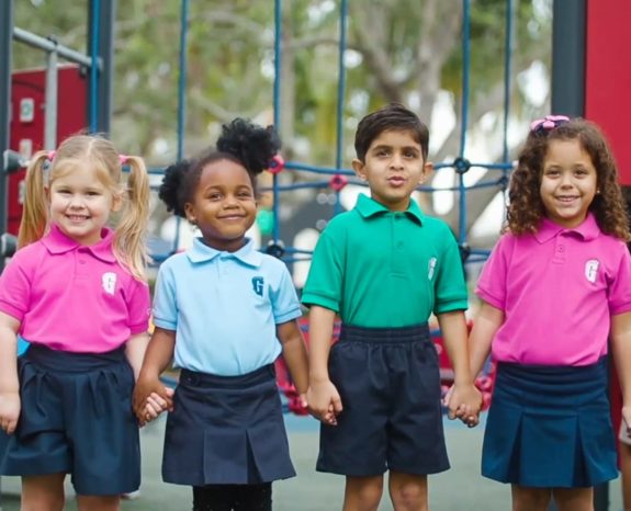 Four diverse children holding hands by the playground