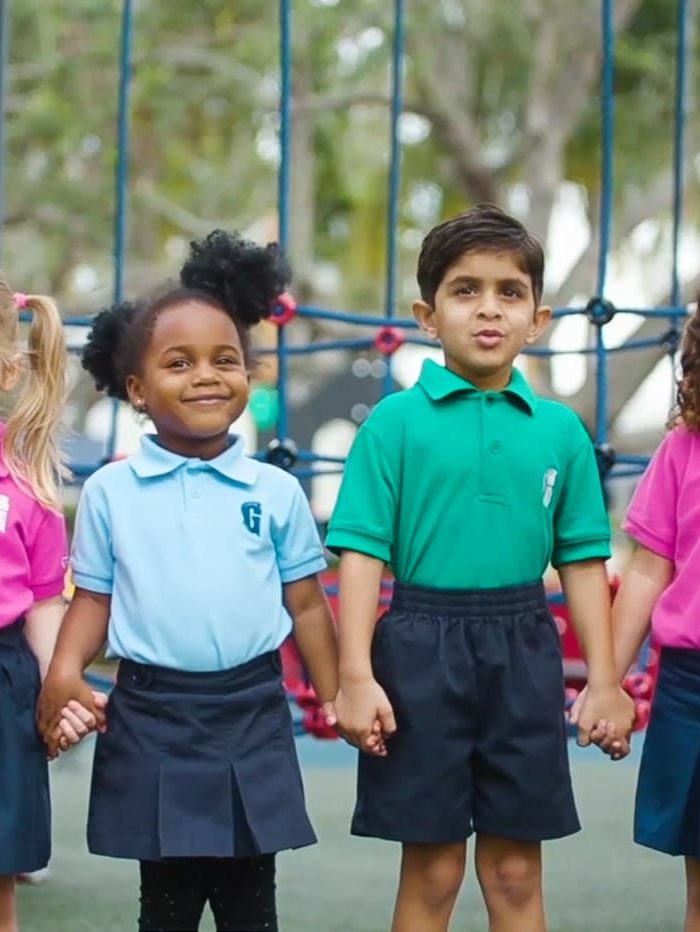Four diverse children holding hands by the playground