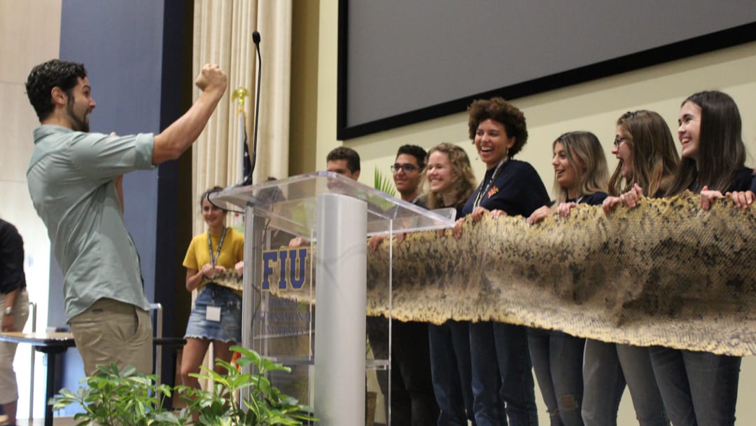 Upper school students in field studies holding a large snake skin