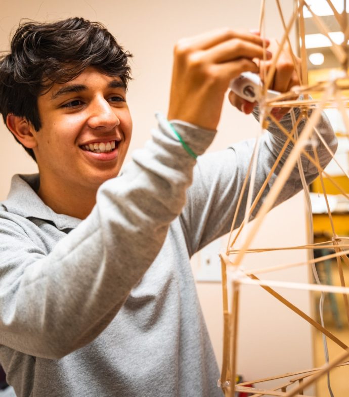 student glueing a wooden sculpture