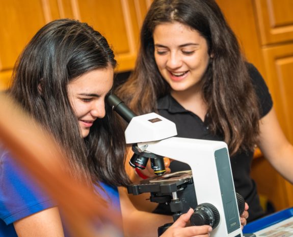 Two girls looking through a microscope