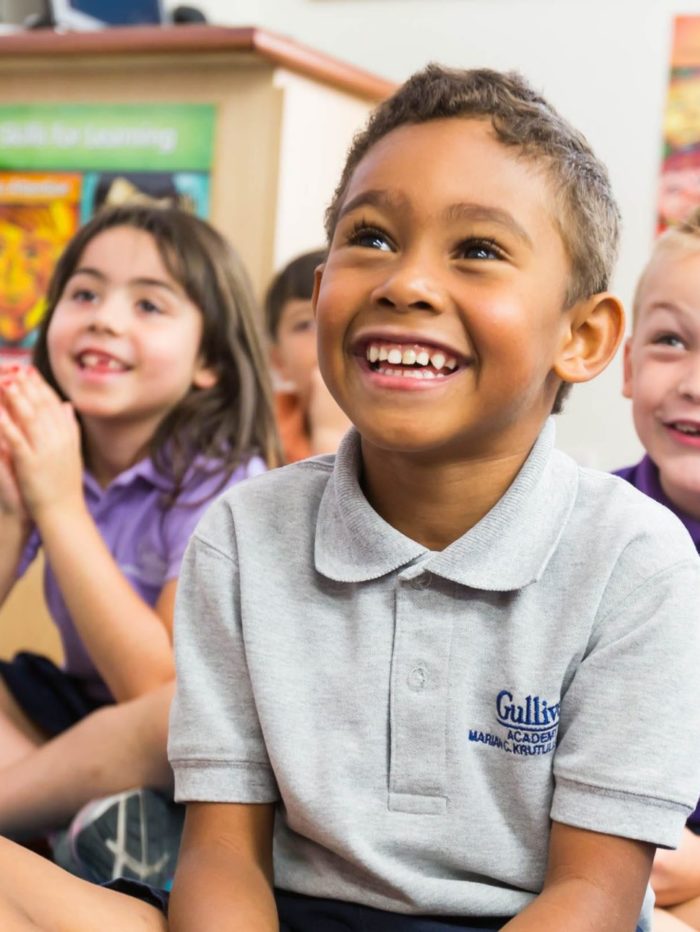 Primary school kids sitting on the floor smiling