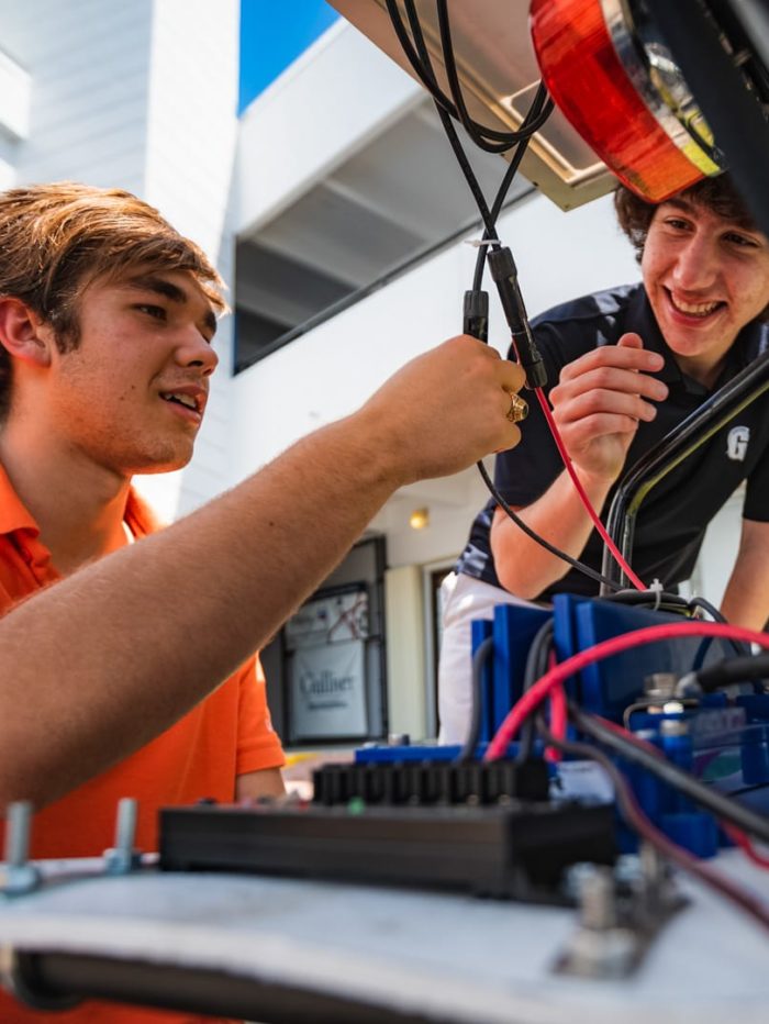 Two students connecting wires for a solar vehicle project
