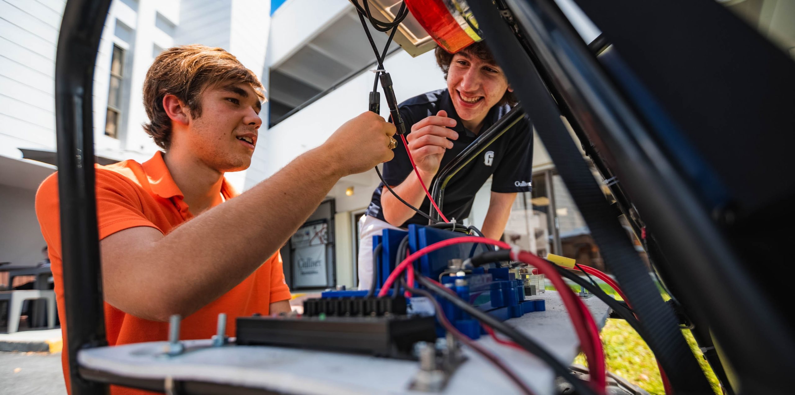 Two students connecting wires for a solar vehicle project
