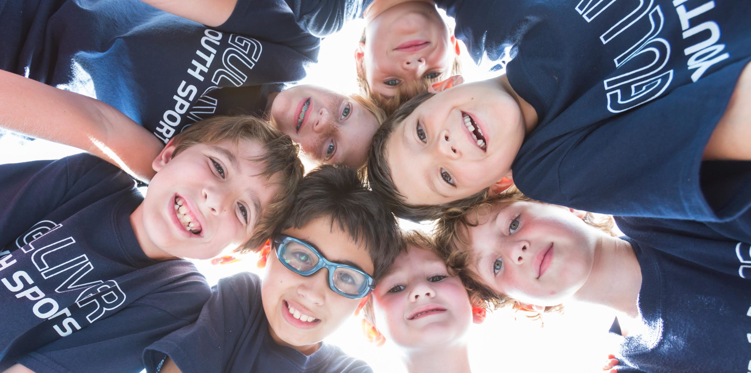 Young students in a circle smiling and looking down
