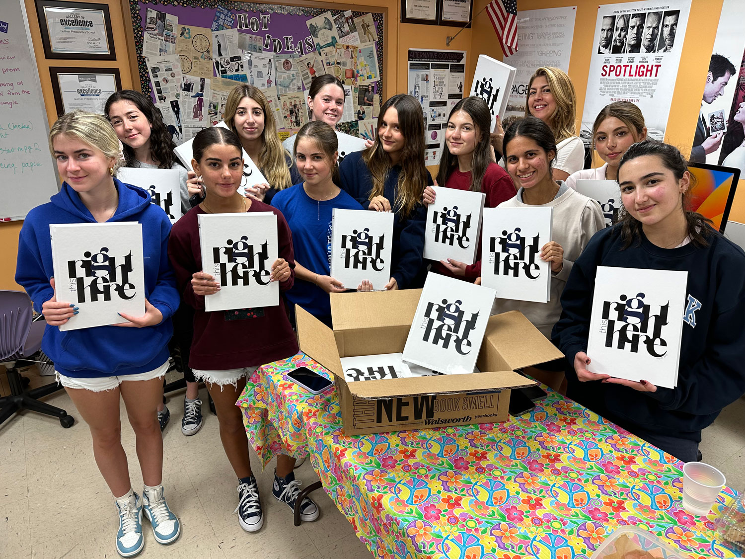 Thirteen people stand in a classroom holding canvases with “right life” printed on them; a box of canvases sits on a colorful table.