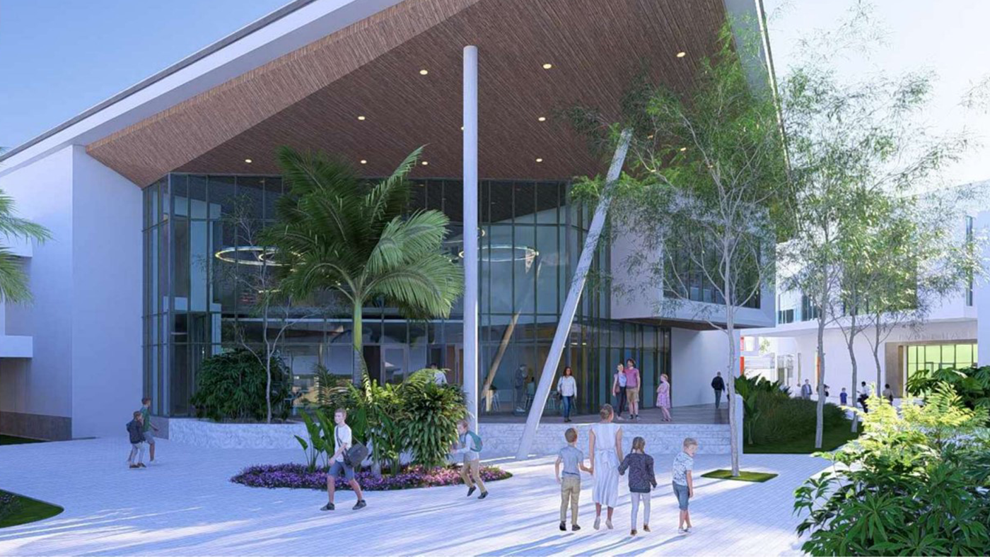 Modern building with large glass windows and angled roof, surrounded by greenery. Several people, including children, walk and gather in the courtyard outside.