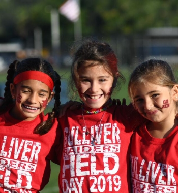 Three girls smiling and wearing raider's shirts