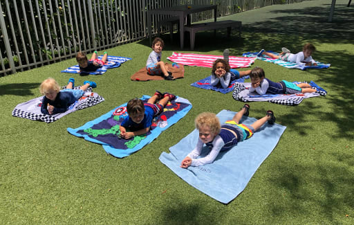 Kids laying on towels in the sun.