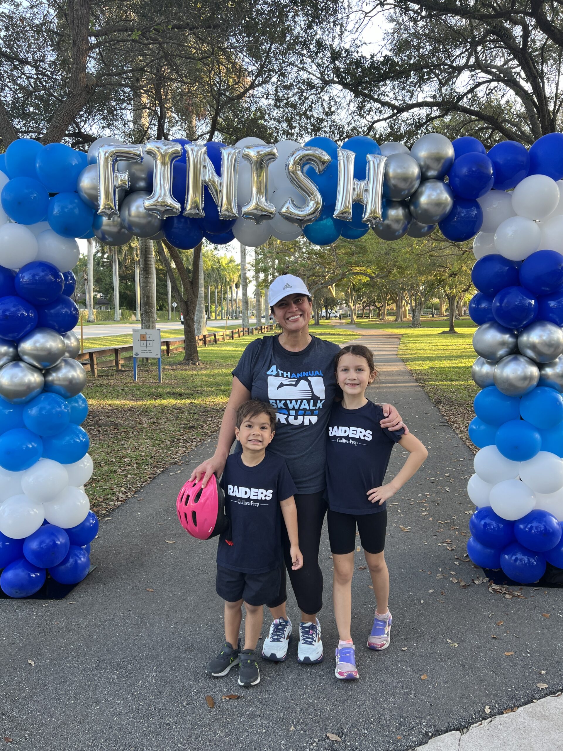 A woman and two children stand under a “FINISH” balloon arch at the 4th Annual Skywalk Run, an event supported by staff pursuing private school careers.